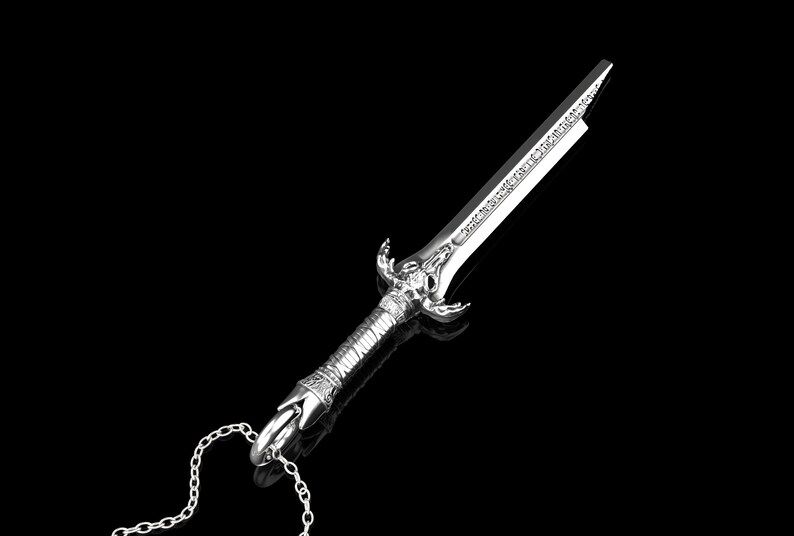 K&ouml;nnte beinhalten: Eine silberne Schwertpendantkette mit einem detaillierten Design und einer Kette. Das Schwert hat eine spitze Spitze und einen dekorativen Griff.