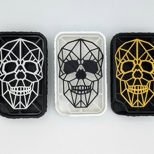 May include: Three geometric skull designs in black, white, and gold. Each skull is made of a geometric pattern of triangles and is framed in a black plastic frame.