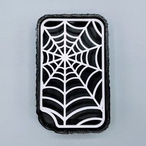Op de afbeelding: Zwarte telefoonhoes met een wit spinnenwebontwerp.