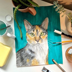 K&ouml;nnte beinhalten: Ein Gem&auml;lde einer dreifarbigen Katze mit gr&uuml;nen Augen auf einem t&uuml;rkisfarbenen Hintergrund. Die Katze schaut direkt auf den Betrachter.