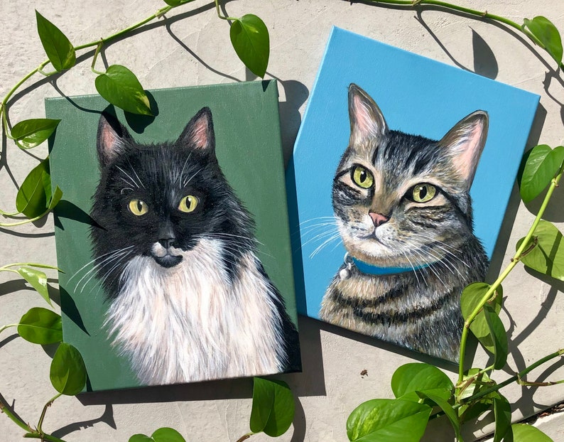 K&ouml;nnte beinhalten: Zwei Katzengem&auml;lde auf Leinw&auml;nden. Die Katze links ist schwarz-wei&szlig; mit einer wei&szlig;en Brust und einem gr&uuml;nen Hintergrund. Die Katze rechts ist getigert mit einem blauen Hintergrund.