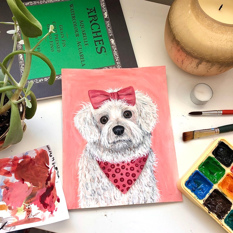 K&ouml;nnte beinhalten: Ein Gem&auml;lde eines wei&szlig;en Hundes mit einer rosa Schleife und einem roten Bandana mit wei&szlig;en Punkten auf rosa Hintergrund.