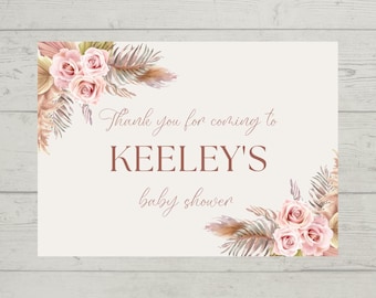 May include: Thank you for coming to KEELEY'S baby shower sign with a floral design featuring pink roses and dried pampas grass.