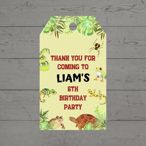 May include: A yellow gift tag with a jungle theme, featuring a snake, spider, frog, lizard, turtle, and tropical leaves. The text reads "THANK YOU FOR COMING TO LIAM'S 6TH BIRTHDAY PARTY" in red.