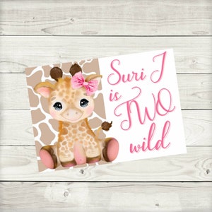 May include: A cute giraffe with a pink bow sits on a brown and white patterned background. The text "Suri is Two wild" is written in pink cursive.