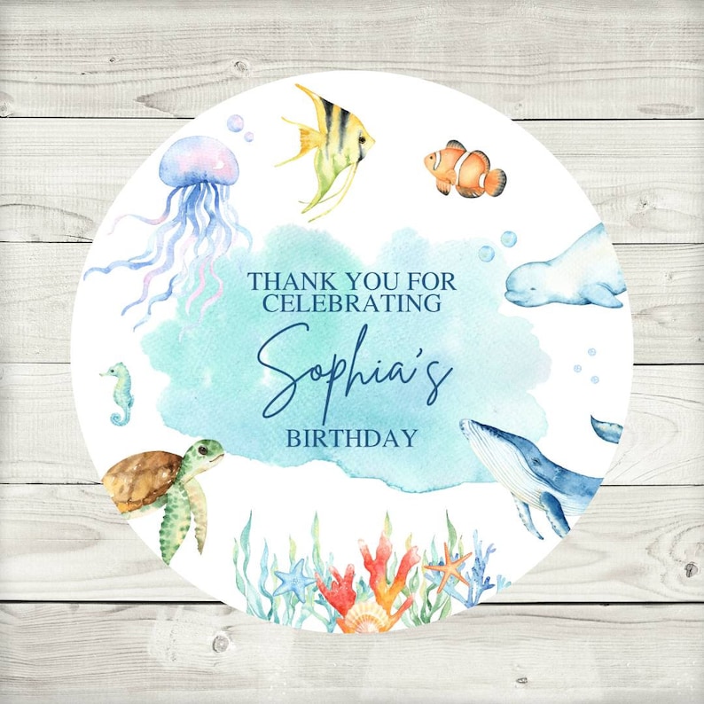 May include: Round sticker with a watercolor design featuring a blue whale, a seahorse, a turtle, a jellyfish, a clownfish, a beluga whale, and coral. The text "Thank you for celebrating Sophia's Birthday" is written in blue.