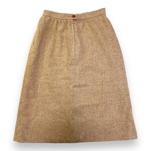 May include: A brown tweed skirt with a zipper closure and a button at the top.