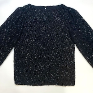 May include: A black long-sleeved sweater with a sparkly texture.