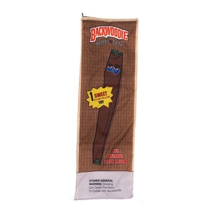 May include: A brown and tan plush pillow shaped like a cigar with a cartoon face. The pillow has the text "Backwoodie Dazeds City" and "All Natural Plush Pillow" printed on it.