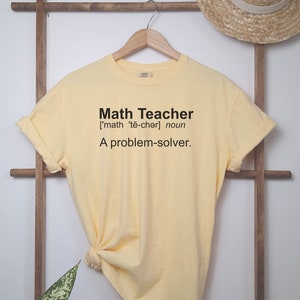May include: A yellow t-shirt with the text "Math Teacher ['math 'te-chǝr] noun A problem-solver." printed on the front.
