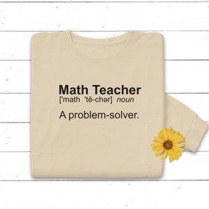 May include: A beige sweatshirt with the text "Math Teacher ['math 'te-chǝr] noun A problem-solver." printed on the front.