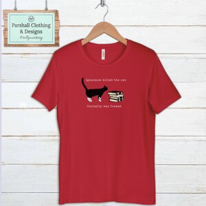 May include: Red t-shirt with a black and white cat illustration and the text "Ignorance killed the cat. Curiosity was framed."