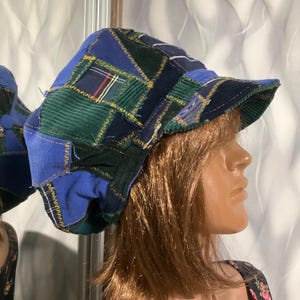 May include: A blue, green, and black patchwork newsboy cap with a slightly curved brim. The cap is made of different fabrics, including corduroy and plaid.