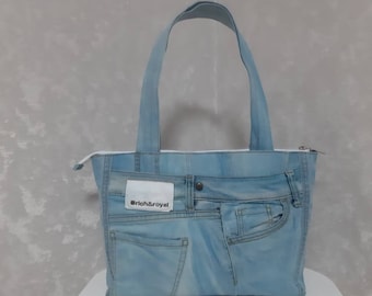 May include: Light blue denim tote bag with a zipper closure and two handles. The bag is made from recycled jeans and features the original pockets and a white label that reads "rich&royal".