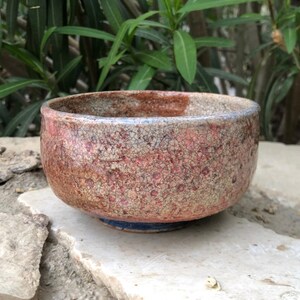 May include: A small, brown and white ceramic bowl with a crackled glaze. The bowl has a blue rim and a slightly rounded base.