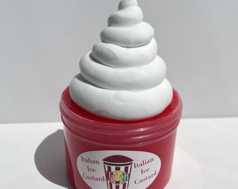 Può includere: Un contenitore di plastica rosso con una copertura di panna montata bianca. Il contenitore ha un'etichetta che dice "Italian Ice Custard" e un logo con la parola "Jaden".