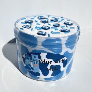 May include: Blue and white slime in a clear container with a blue cow milk label. The slime is topped with blue sprinkles and miniature blue milk cartons.