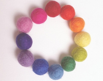 May include: A circle of colorful felt balls in shades of red, orange, yellow, green, blue, purple, and pink. The balls are arranged in a rainbow pattern.