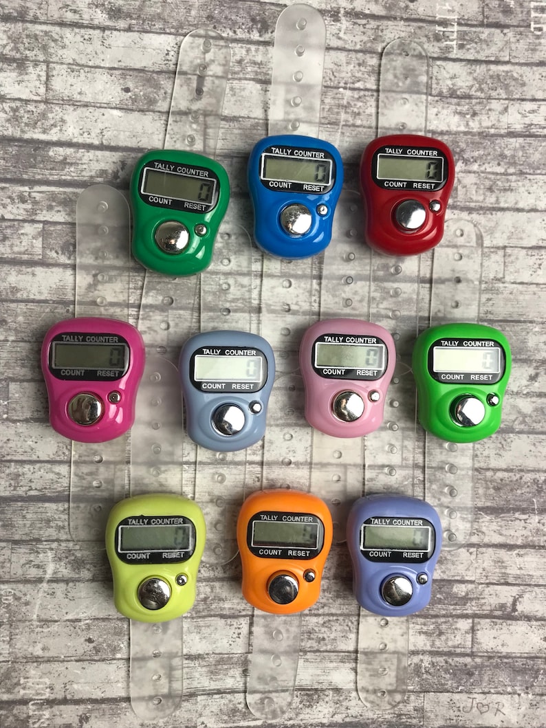 May include: Ten colorful digital tally counters with a clear plastic wrist strap. Each counter has a button labeled "COUNT" and "RESET".