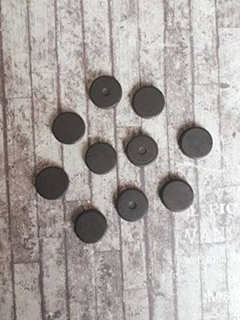 May include: Ten round black magnets with a hole in the center of some of them.