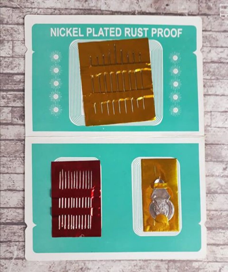 K&ouml;nnte beinhalten: Eine blaue und wei&szlig;e Karte mit dem Text "Nickel Plated Rust Proof" darauf gedruckt. Die Karte hat zwei F&auml;cher, die jeweils eine Packung Nadeln enthalten. Eine Packung ist golden und die andere rot.