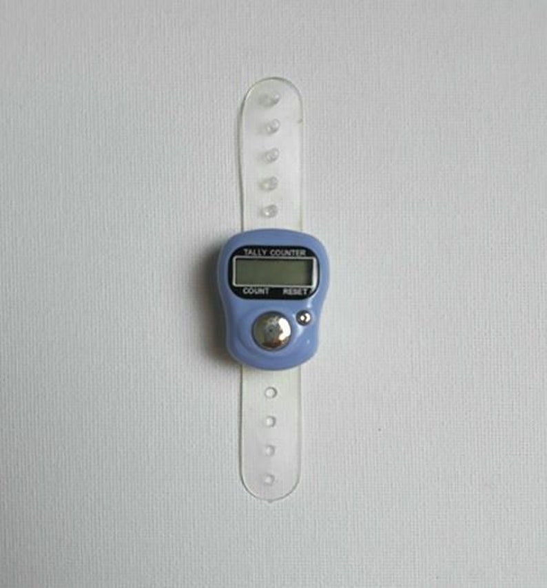 May include: A blue digital tally counter with a clear plastic strap. The counter has buttons labeled "Count" and "Reset" and a display that reads "Tally Counter".