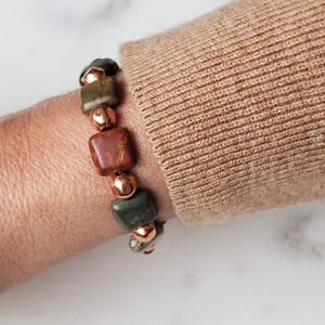 May include: A bracelet featuring square green and brown stones interspersed with copper beads.