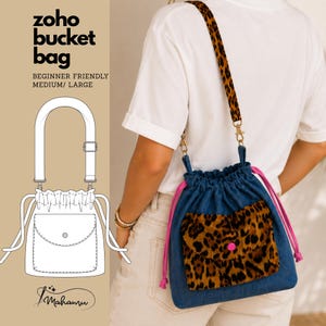 May include: A blue denim bucket bag with a leopard print front pocket, a matching leopard print adjustable shoulder strap, and bright pink drawstring cords. The bag features a flap pocket with a pink button closure and gold-tone hardware.