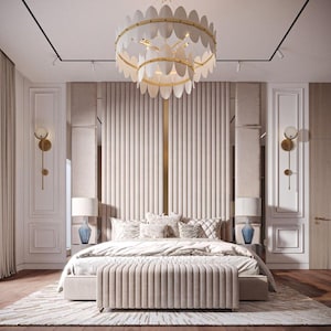 Könnte beinhalten: Ein luxuriöses Schlafzimmer mit einem großen Bett, das ein weißes Kopfteil mit vertikalen Kanälen, eine weiße Bettdecke und eine Vielzahl von Kissen aufweist. Das Bett steht mittig im Raum, über ihm hängt ein großer, verzierter Kronleuchter. Die Wände sind in einem hellen Beige gestrichen und der Boden ist aus dunklem Holz.
