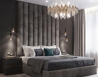 May include: A gray upholstered bed with a tall headboard and a crystal chandelier hanging above it. The bed has a gray duvet and white pillows. The room is decorated in a modern style with gray walls and a gray rug.