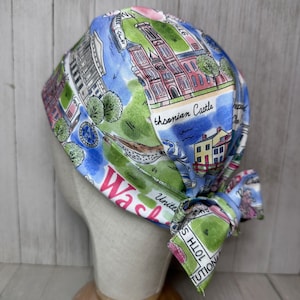 May include: A colorful bandana with a map of Washington, D.C. printed on it. The bandana is tied around a mannequin's head. The bandana features landmarks like the Smithsonian Castle and the Washington Monument.