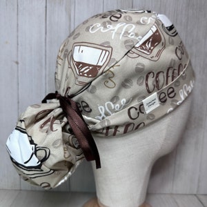 Peut inclure: Un bonnet de travail brun et beige avec un imprimé de grains de café et de tasses à café. Le bonnet a une cravate brune et le texte "Coffee" est imprimé sur le bonnet.