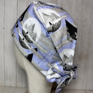 May include: A blue and white patterned surgical scrub hat with a geometric design. The hat has a tie at the back.