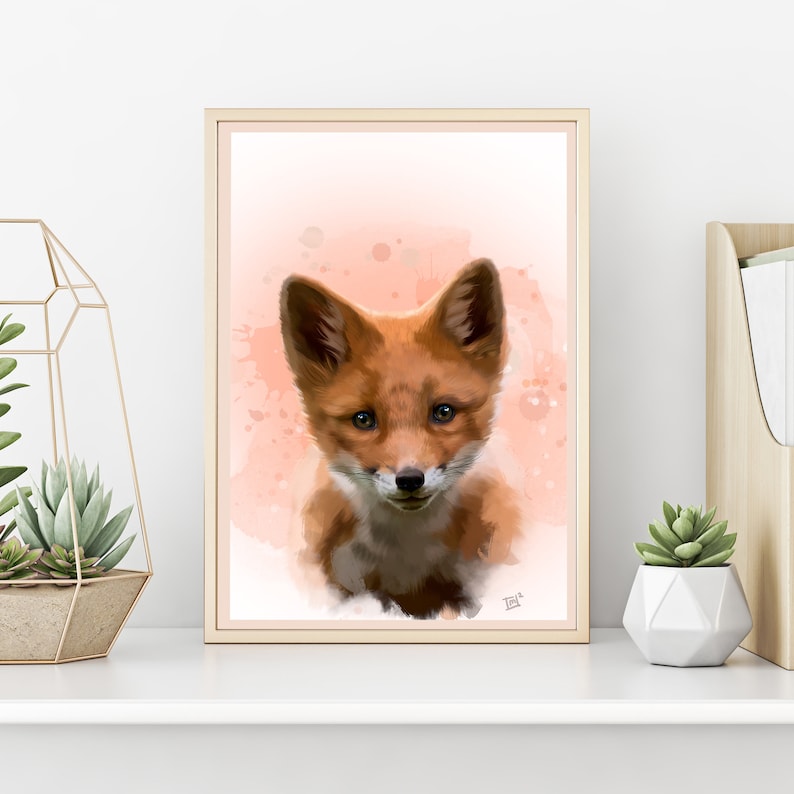 Puede incluir: Impresi&oacute;n art&iacute;stica enmarcada que presenta una pintura de acuarela de un cachorro de zorro. El zorro tiene pelaje naranja y blanco, con un fondo rosa y melocot&oacute;n suave. La obra de arte se exhibe en una estanter&iacute;a blanca con plantas decorativas.