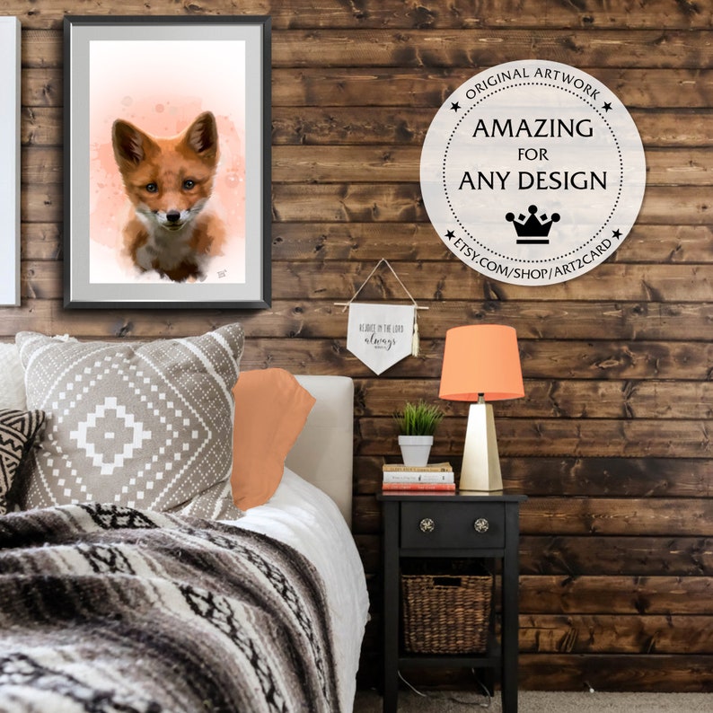 Puede incluir: Una impresi&oacute;n en acuarela enmarcada de un zorro con pelaje naranja y marr&oacute;n, sobre un fondo color melocot&oacute;n. La obra de arte cuelga sobre una cama con almohadas estampadas y una manta tejida. Tambi&eacute;n se ve una mesita de noche con una l&aacute;mpara y una pancarta.