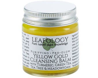 May include: A small glass jar with a silver lid containing yellow cleansing balm. The label reads "LEAFOLOGY Pure naked plant knowledge PURIFYING PRO-GLOW YELLOW GOLD CLEANSING BALM WITH TURMERIC, GREEN TEA, TEA TREE & MEADOWFOAM".