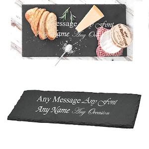 May include: A black slate serving board with a white inscription that reads "Any Message Any Font Any Name Any Occasion". The board is shown with a variety of cheese, bread, and other food items.