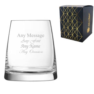 May include: A clear glass tumbler with a wide base and a slightly flared top. The glass is engraved with the text "Any Message Any Font Any Name Any Occasion". The glass is packaged in a black box with a gold geometric pattern.