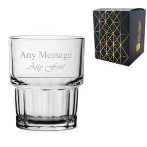 Peut inclure: Un verre à whisky en verre transparent avec un motif côtelé. Le verre est gravé avec le texte "Any Message Any Font". Le verre est emballé dans une boîte noire avec un motif géométrique doré.