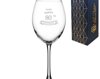 May include: A clear glass wine glass with a personalized inscription that reads "NAME HAPPY 80Th BIRTHDAY". The glass is in a blue and gold gift box.