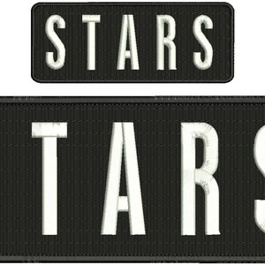 Könnte beinhalten: Zwei schwarze rechteckige Patches mit weiß gesticktem Text, der "STARS" lautet. Der obere Patch ist kleiner als der untere Patch.