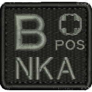 May include: A square, black embroidered patch featuring the text "B POS NKA" in light grey thread. The design includes a stylized cross symbol above the letters "POS". The patch has a textured appearance.