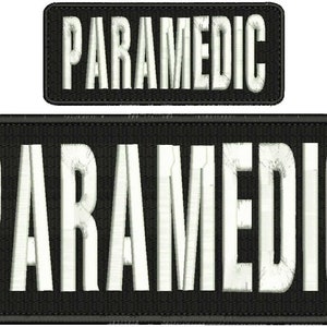 May include: Two black embroidered patches with white lettering that reads "PARAMEDIC". The top patch is smaller than the bottom patch.
