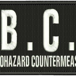 Puede incluir: Parche negro con texto bordado en blanco "U.B.C.S." y las palabras "Umbrella Biohazard Countermeasure Service" debajo.