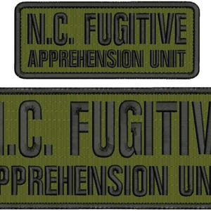 Peut inclure: Deux écussons brodés vert olive. Le plus grand porte l'inscription "N.C. FUGITIVE APPREHENSION UNIT" en lettres noires. Un plus petit écusson avec le même texte est au-dessus. Les deux ont des bordures noires.