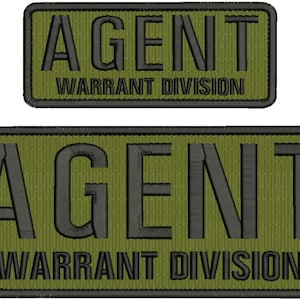 Puede incluir: Dos parches bordados verdes con texto negro. El parche superior dice "AGENT WARRANT DIVISION". El parche inferior dice "AGENT WARRANT DIVISION".