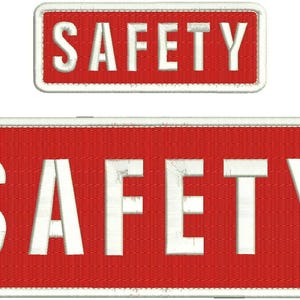 May include: Two red rectangular patches with white borders and white text that reads "SAFETY" in all caps.