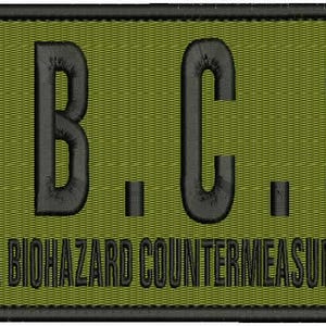 May include: A green patch with black text that reads "U.B.C.S." and "UMBRELLA BIOHAZARD COUNTERMEASURE SERVICE".