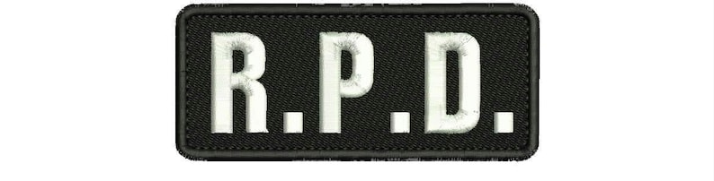 Op de afbeelding: Zwarte rechthoekige patch met witte geborduurde letters die "R.P.D." lezen