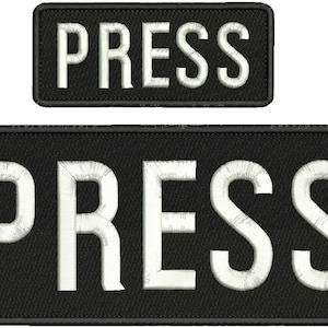 May include: Two black rectangular patches with white embroidered text that reads "PRESS". The top patch is smaller than the bottom patch.